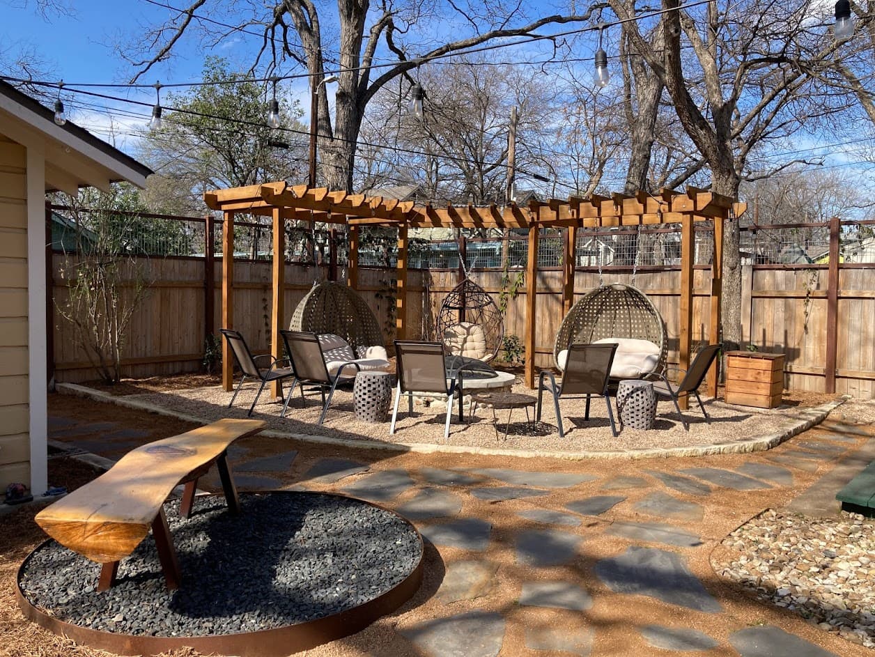 Complete outdoor living space with stone patio, pergola, and native plantings, Ave H project in Austin TX