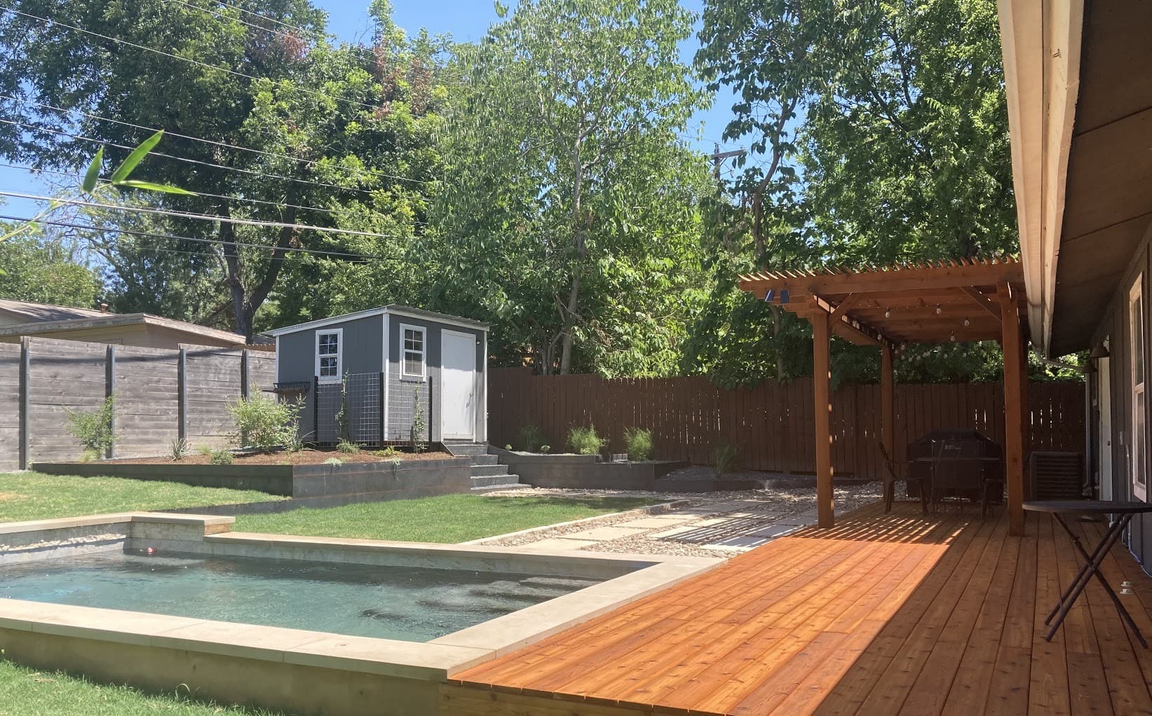 Multi-level hardscape design with cedar deck, stone patio, and landscape lighting integration